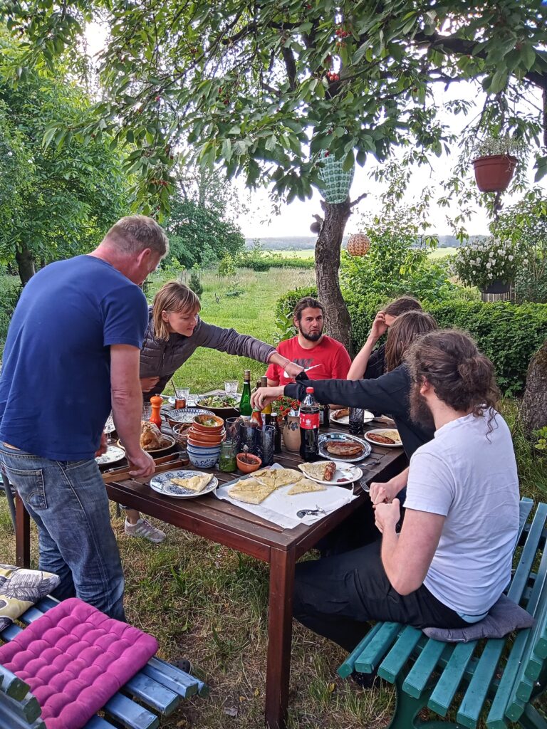 5 Menschen sitzen am gedeckten Tisch im Garten