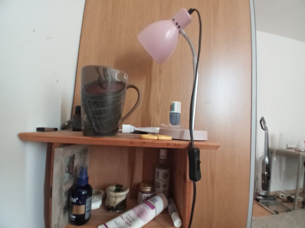 Kaffeetasse neben einer Lampe auf einem Regal